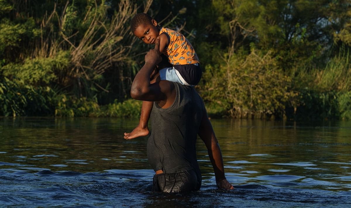 A father carries his son across the water at the US-Mexico border on the Rio Grande as seen from Ciudad Acuna, Coahuila state, Mexico. Credit: AFP Photo
