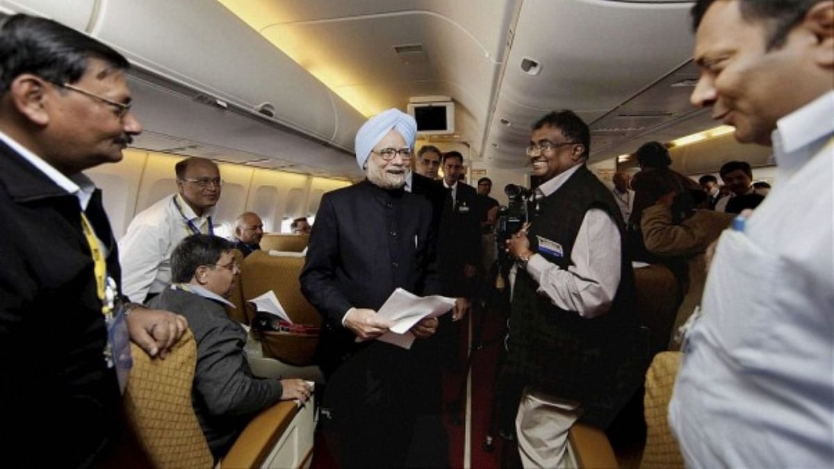 PM Manmohan Singh is also seen working with journalists inside the flight. Credit: Twitter/@KiranKS