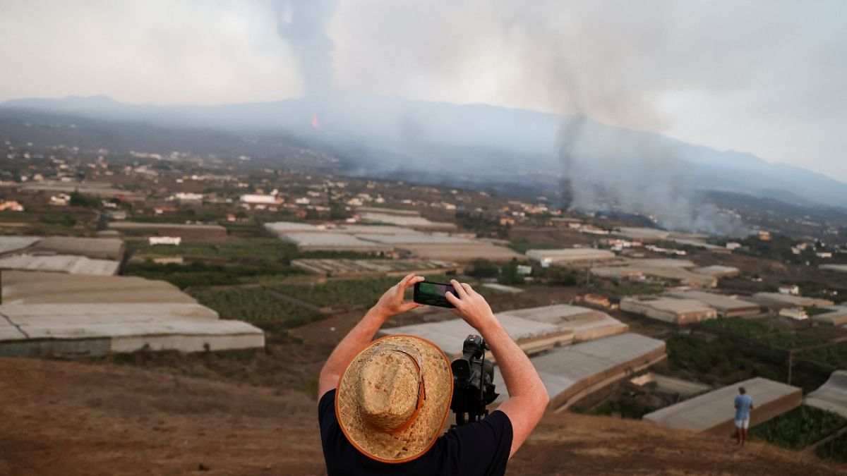 A man takes a picture as lava and smoke rise following the eruption of a volcano on the Canary Island of La Palma, in La Todoque, Spain. Credit: Reuters Photo