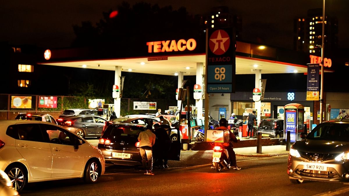 People push as a car, which has run out of petrol, the final few meters on to the forecourt as vehicles queue to refill at a Texaco fuel station in south London, Britain. Credit: Reuters Photo
