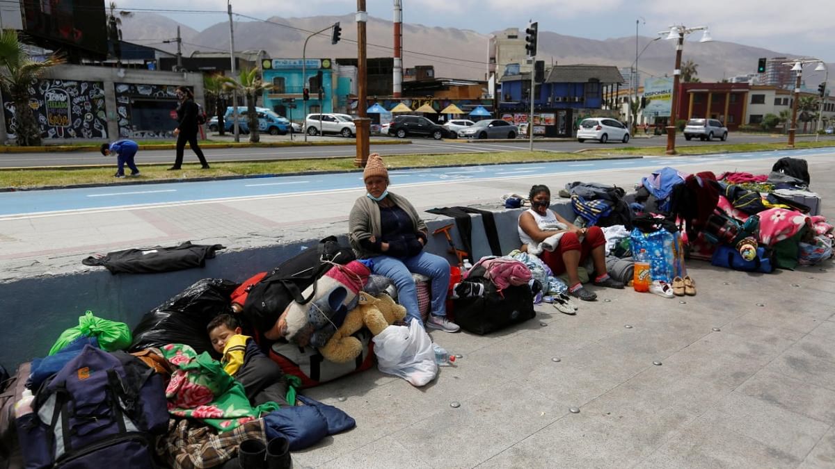 Venezuelan migrants sit along a street next to the ocean after their camp was destroyed during violent anti-immigration protests, in Iquique, Chile. Credit: Reuters Photo