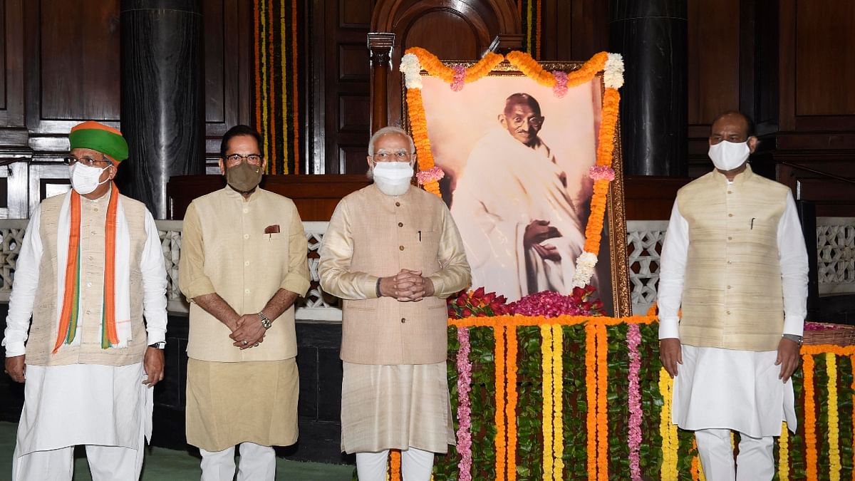 Union Minority Affairs Minister Mukhtar Abbas Naqvi, Prime Minister Narendra Modi and Lok Sabha Speaker Om Birla pose for a photo after paying tribute to Mahatma Gandhi on his birth anniversary at Parliament House, in New Delhi. Credit: PTI Photo