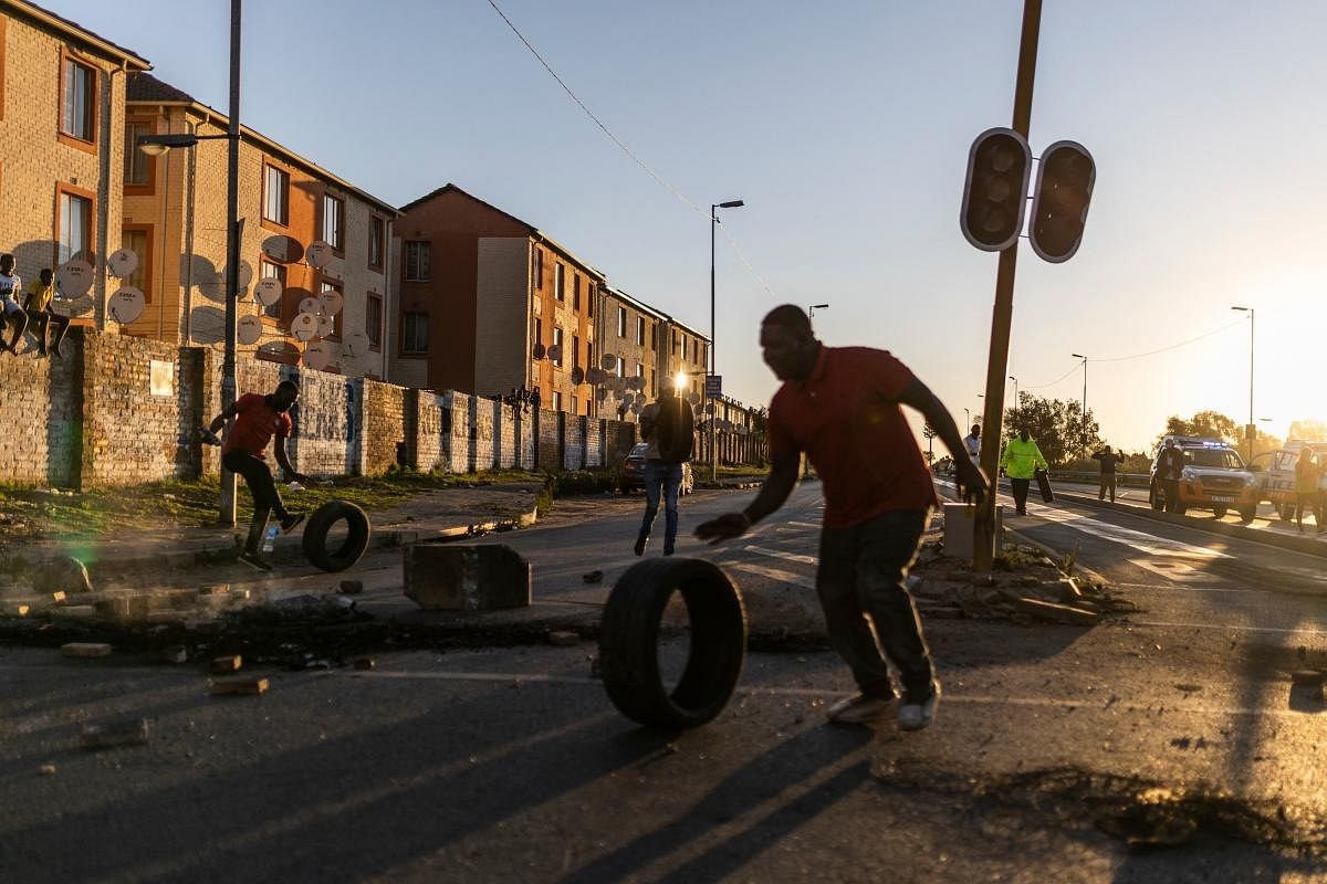 Protestors push tyres to set a roadblock in Penyville, Soweto during a protest against the violence and insecurity that afflicts the area on in Soweto. Credit: AFP Photo