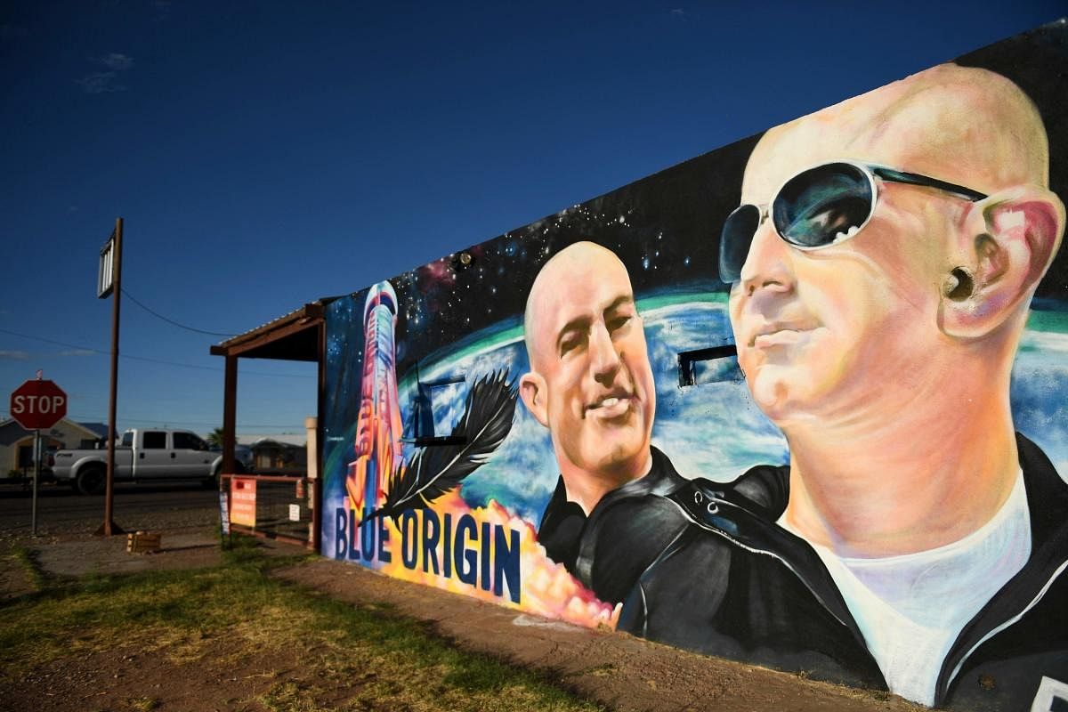 A pickup truck drives past a mural of billionaire Amazon founder Jeff Bezos (R) and his brother Mark Bezos with a Blue Origin rocket in Van Horn, Texas. Credit: AFP Photo