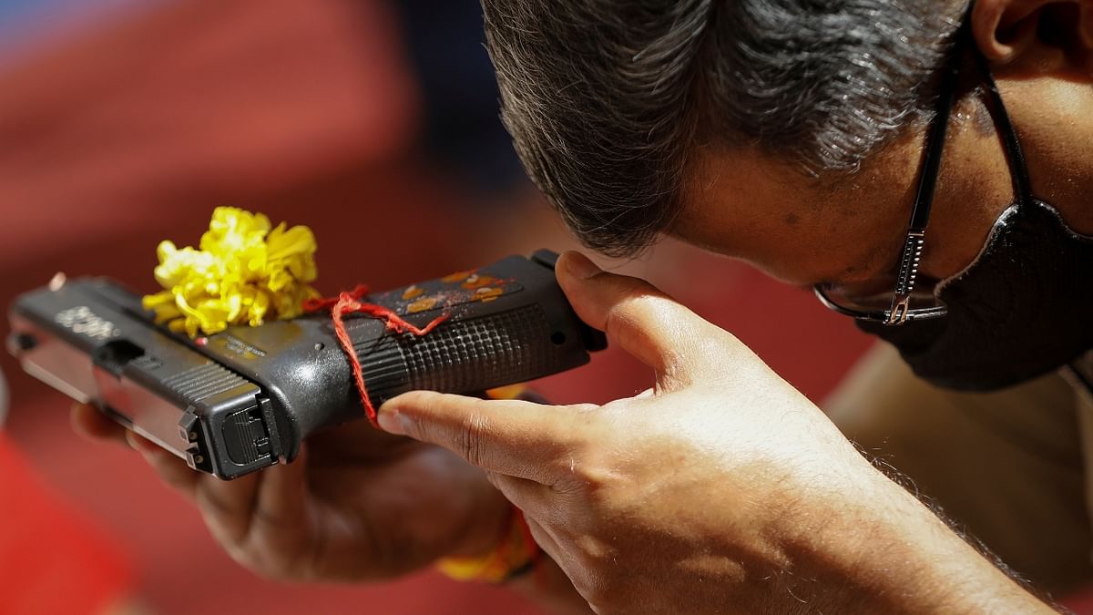 A police officer offers prayer to his weapon as part of a ritual at their headquarters in Ahmedabad. Credit: Reuters Photo