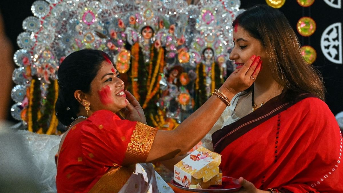 Women play with vermilion on the occasion of Dussehra, at a puja pandal in Delhi. Credit: AFP Photo