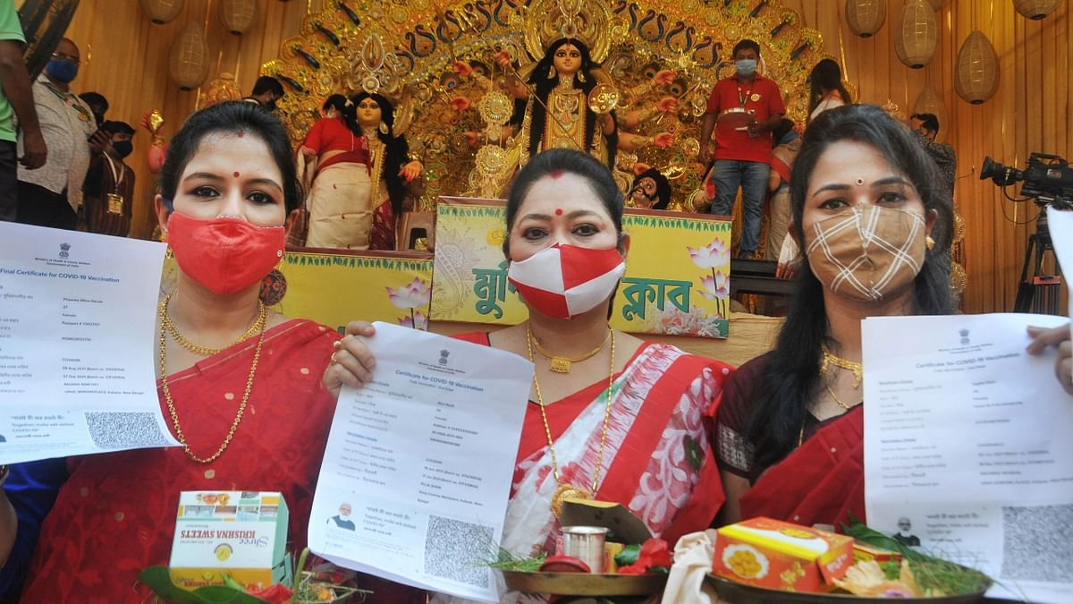 Women in Bengal show their Covid-19 vaccination certificate before participating in 'Sindoor Khela' on the last day of the Durga Puja festival at a community puja pandal in Kolkata. Credit: PTI Photo