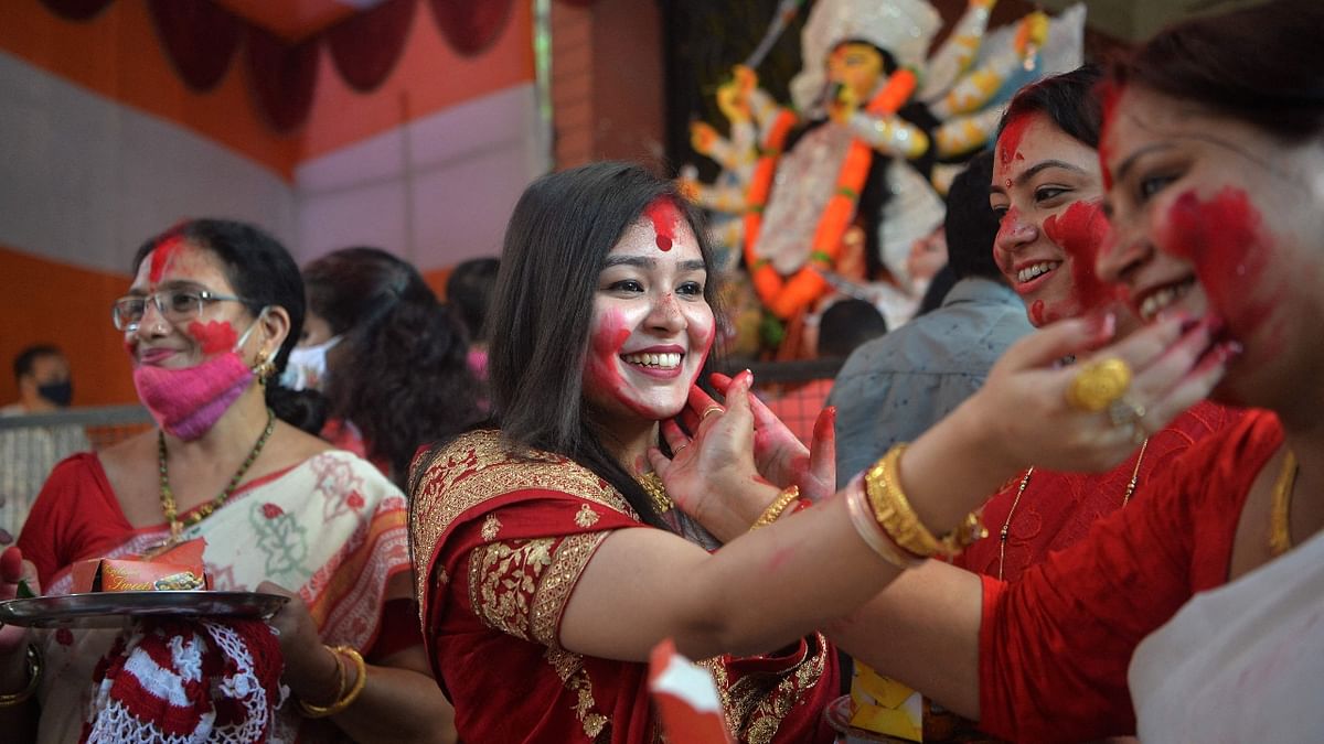 Devotees apply vermilion powder on each other's faces as part of a traditional ritual on the final day of Durga Puja festival in Siliguri. Credit: AFP Photo