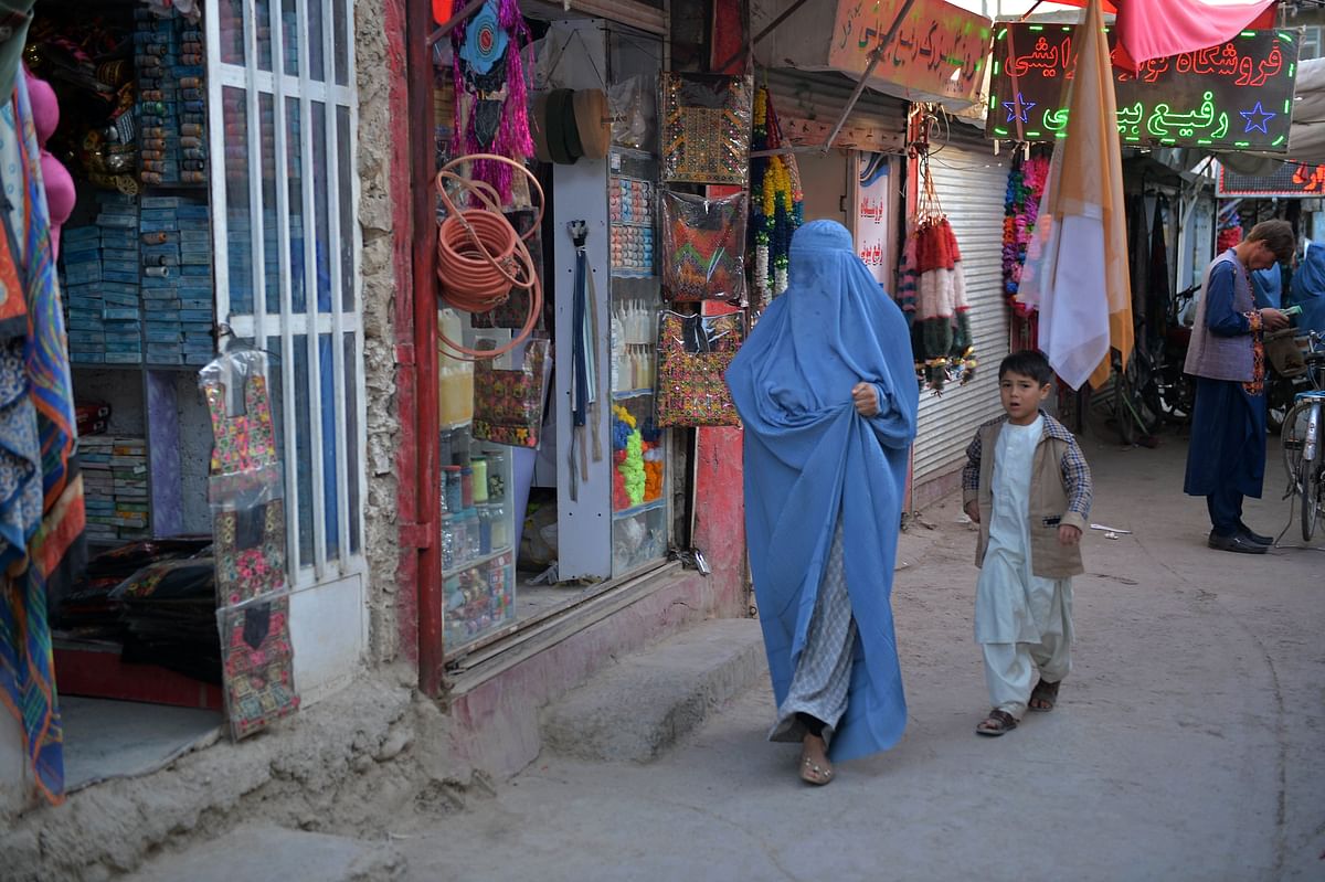 An Afghan burqa-clad woman and a boy walk through a market area in Qala-e-Naw in Badghis province. Credit: AFP Photo