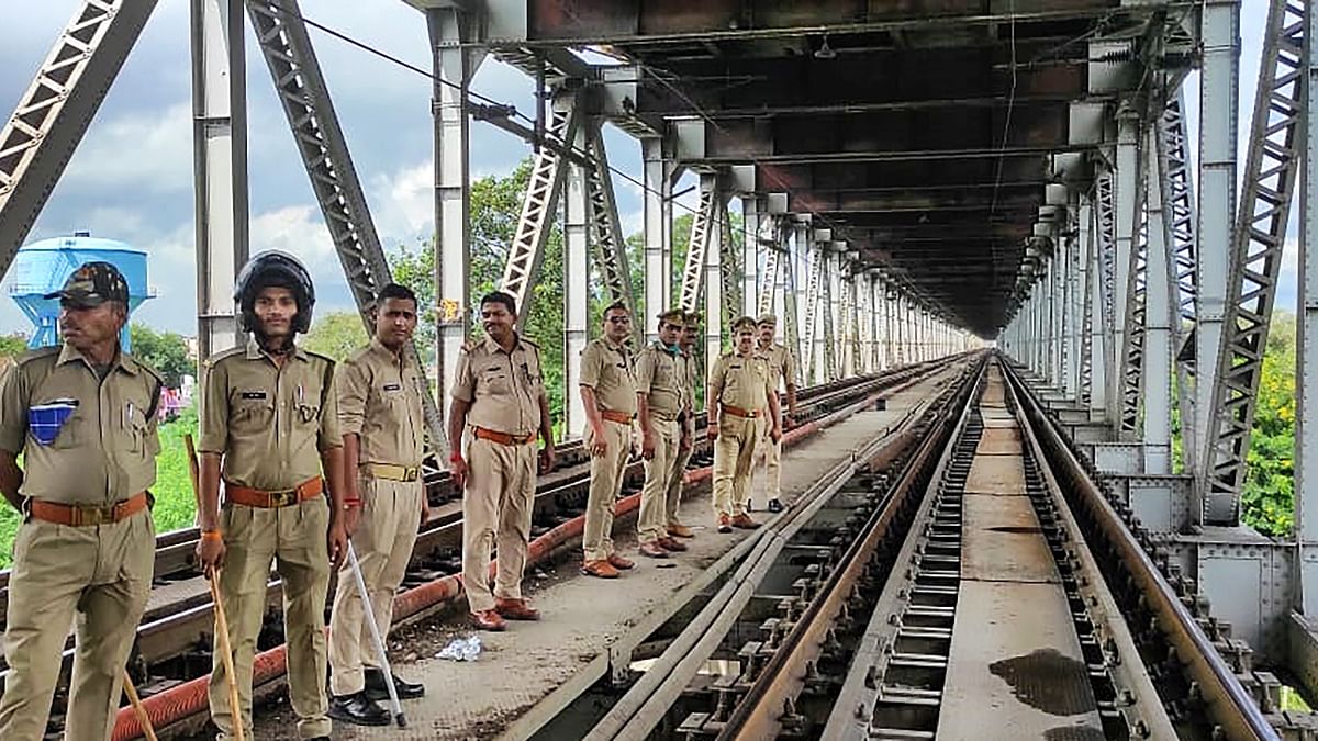 Police personnel stand guard at a railway bridge to prevent farmers from blocking the tracks as part of their 'Rail Roko' protest, in Varanasi. Credit: PTI Photo