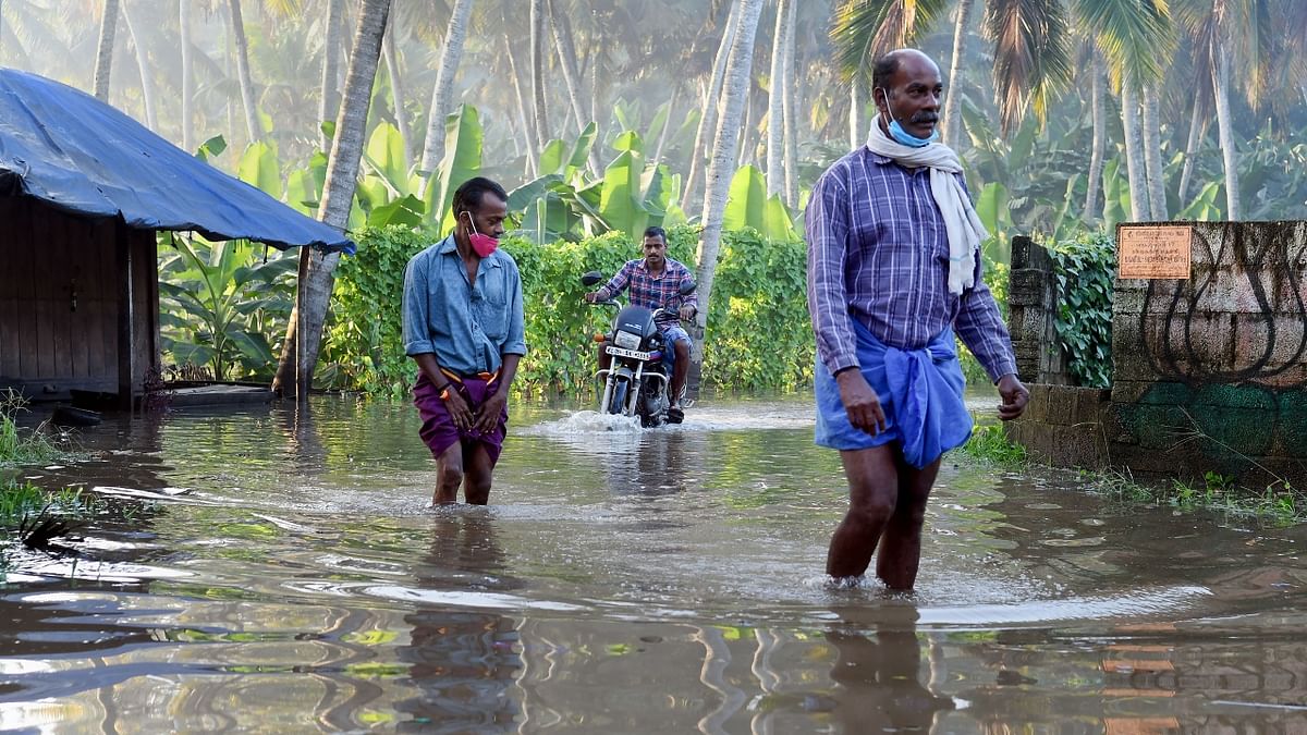 Locals walk through a waterlogged street after heavy rain in Thiruvananthapuram. Credit: PTI Photo