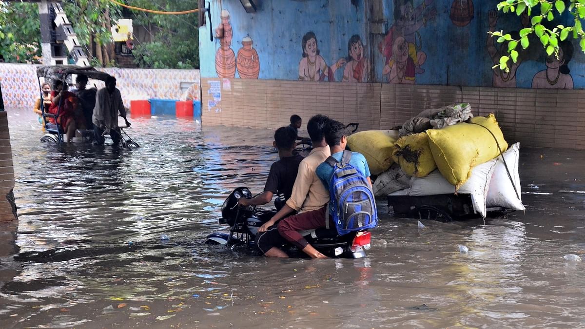 People wade through a flooded street after heavy rainfall in Mathura. Credit: PTI Photo
