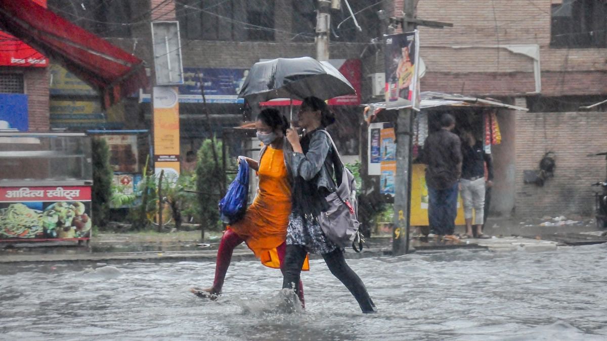 Office-goers cross a water-logged road amid heavy rain in Moradabad. Credit: PTI Photo