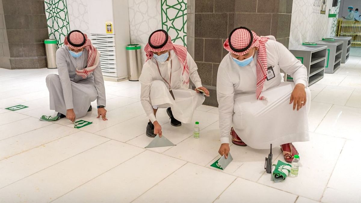 Officials are seen removing social distancing signs at the Grand Mosque in the Saudi holy city of Mecca. Credit: AFP Photo/HO/Saudi General Presidency For the Affairs of the Grand Mosque and The Prophet's Mosque