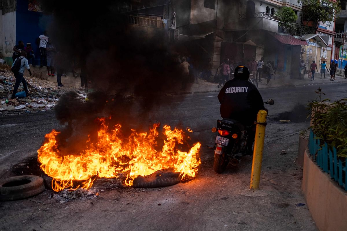 A man in a motorcycle ride past a barricade of burning tires during a demonstration against high prices and fuel shortages in Port-au-Princ