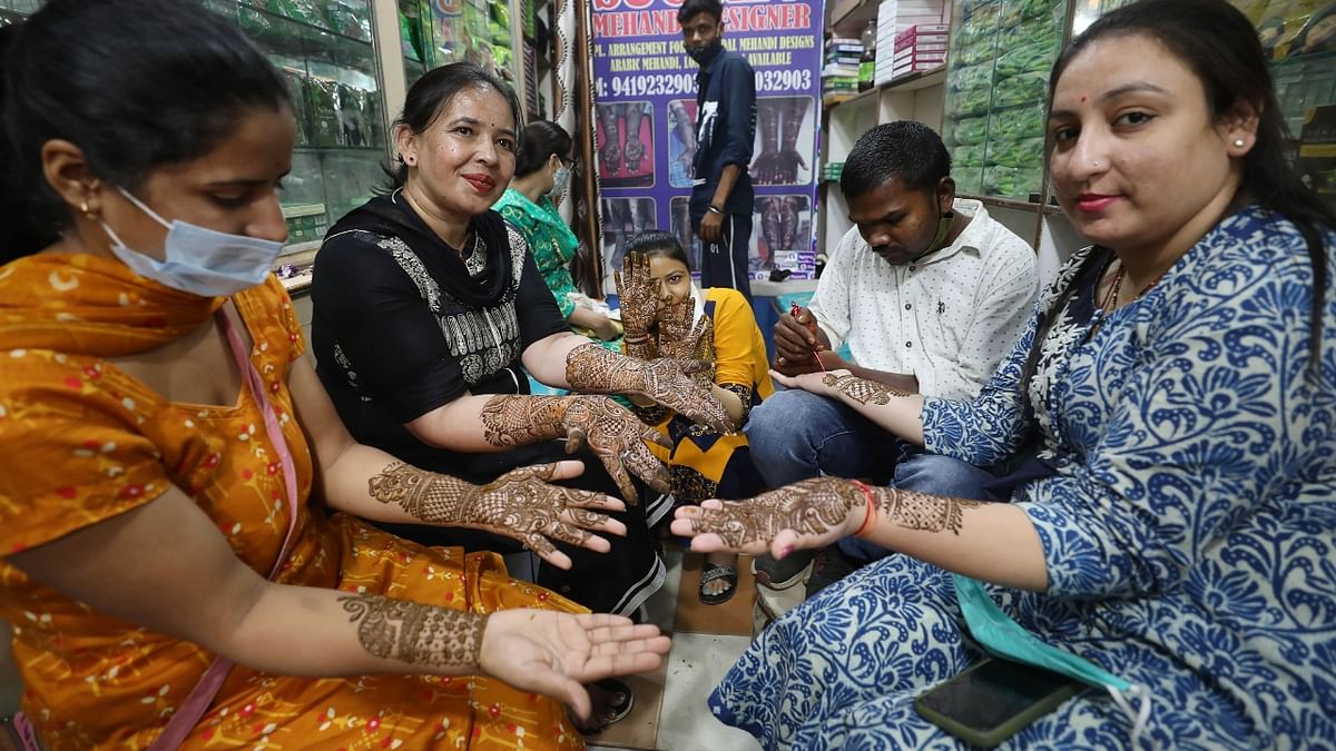 Women pose for a photo after getting mehendi applied on their hands in Jammu. Credit: PTI Photo