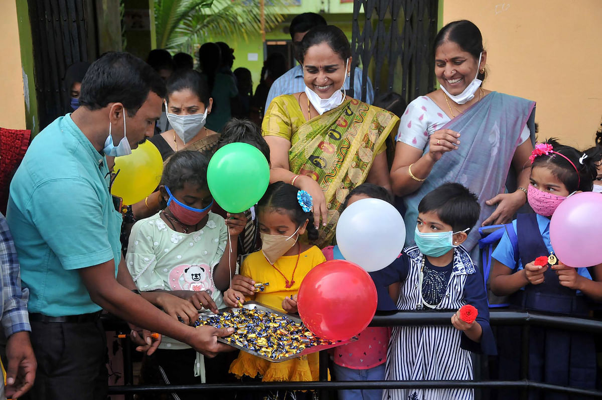 Primary school students greeted by the school authorities with balloons and candies on the first day of their school, in Chikmagalur. Credit: PTI Photo