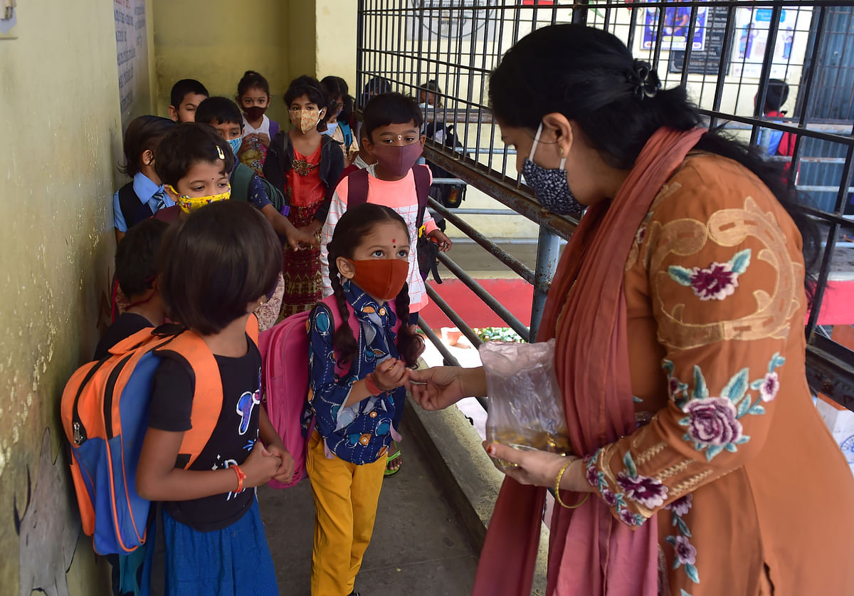 A teacher gives a toffy to a student before she attends a class in Bengaluru. Credit: PTI Photo