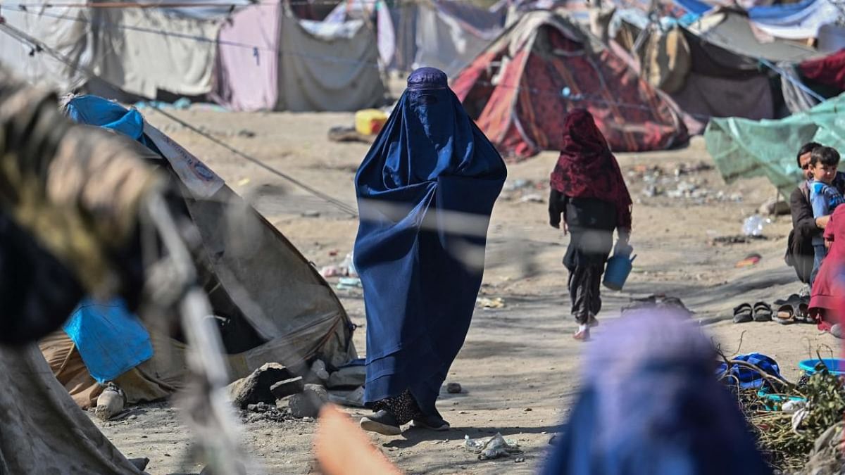 An internally displaced Afghan burqa-clad woman walks inside the Saray Shamali refugee camp in Kabul. Credit: AFP Photo