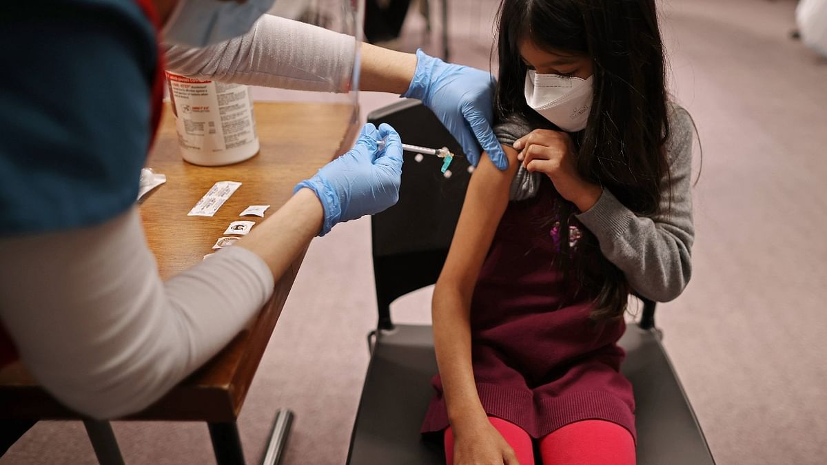 A young girl rolls her sleeves while getting the Pfizer BioNTech Covid-19 vaccine at the Fairfax County Government Center in Annandale, Virginia. Credit: AFP Photo