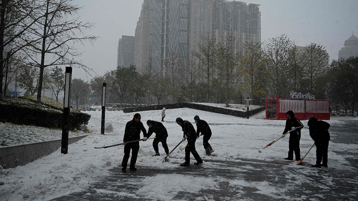 Workers shovel snow in front of a mall in Beijing. Credit: AFP Photo