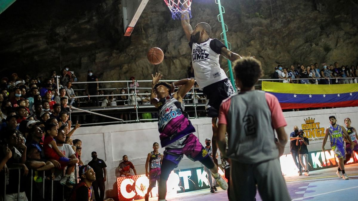 Players in action during a basketball match between the Court Kingz and the neighbourhood team, in the low income neighbourhood of Guarataro, in Caracas, Venezuela. Credit: Reuters Photo