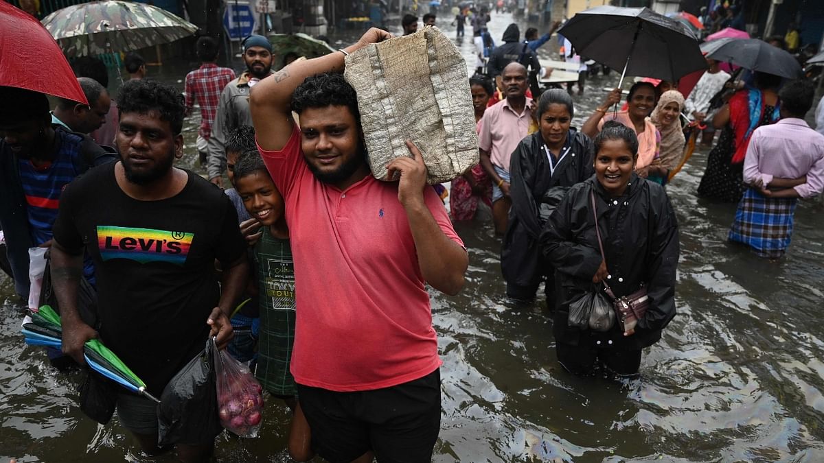 People wade through a flooded street after heavy monsoon rains in Chennai. Credit: AFP Photo