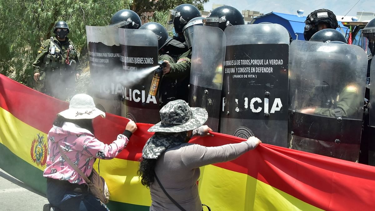 A police officer sprays tear gas at a demonstrator blocking a highway with a Bolivian flag banner during protests against legislation that opposition groups say will hit private property and centralize political power in the hands of the ruling socialist party, in Cochabamba, Bolivia. Credit: Reuters Photo