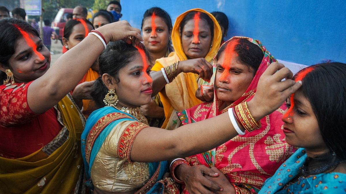 Devotees play with vermilion after performing rituals at an artificial pond to prevent pollution during the Chhath Puja festival, in Kolkata. Credit: PTI Photo