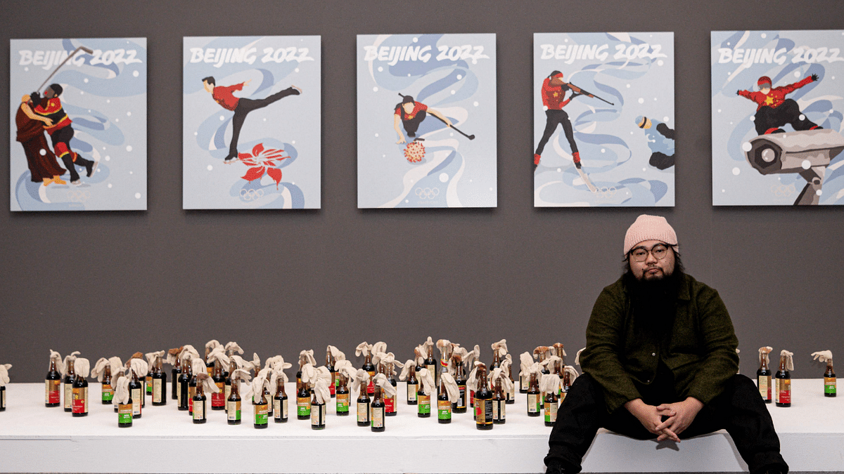 Chinese dissident artist Badiucao poses next to his artwork series inspired by the upcoming 2022 Winter Olympic Games in Beijing, on November 12, 2021 at the exhibition