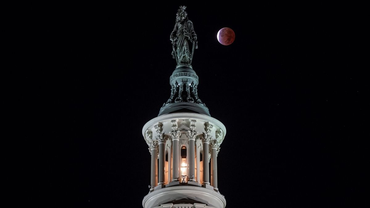 The moon, with a partial lunar eclipse, is seen behind the Statue of Freedom, on Capitol Hill in Washington. Credit: AFP Photo