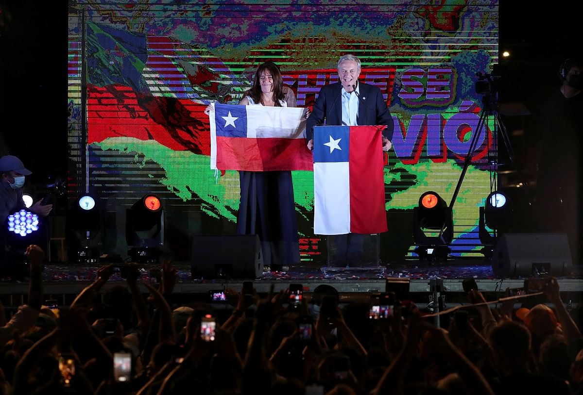 Chilean presidential candidate Jose Antonio Kast speaks as his wife Maria Pia Adriasola Barroilhet holds up Chile's national flag after the partial results of the first round vote during the presidential elections.  Credit: Reuters Photo