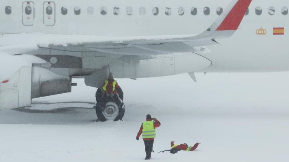 An airport worker sits on the wheel of a parked snow-covered plane as one of his colleague takes a picture of another coworker lying on the snow at Adolfo Suarez Barajas airport, which is suspending flights due to heavy snowfall in Madrid, Spain. Credit: Reuters Photo