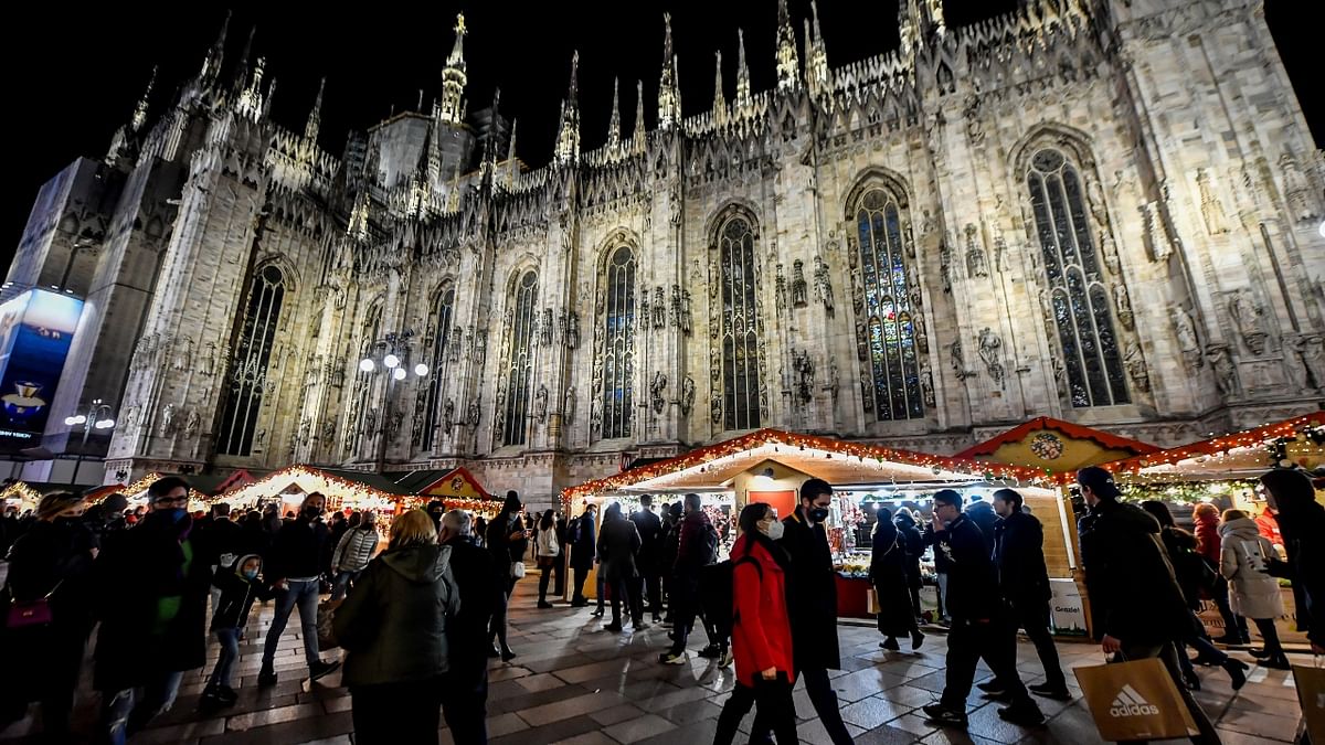 People walk by the Christmas market under the Duomo cathedral in the center of Milan, Italy. Credit: AP Photo