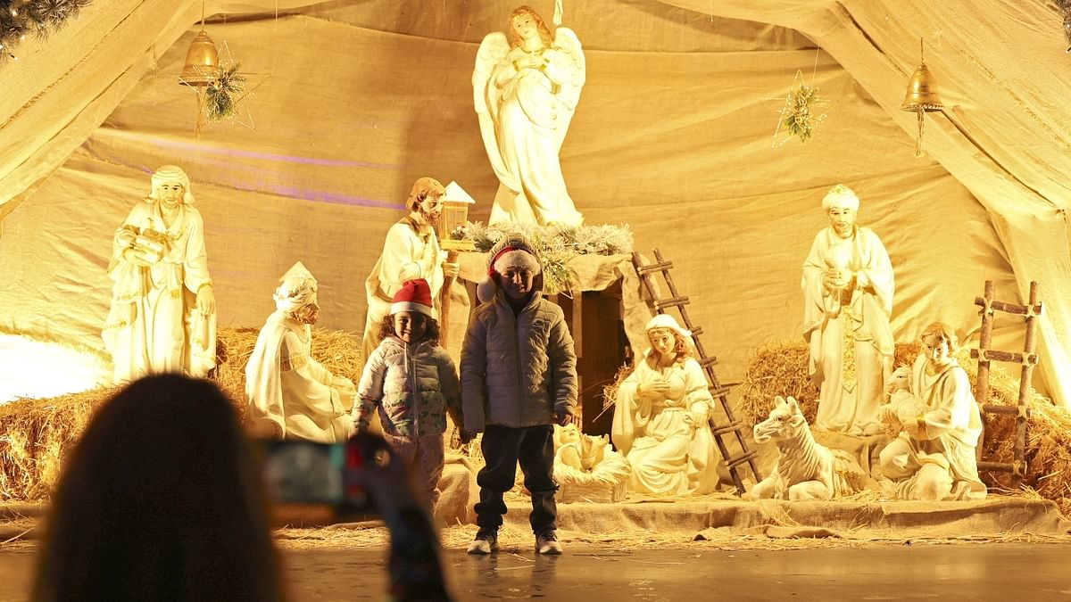 Palestinian take a picture of a child in front of a nativity scene at a Christmas market outside Ramallah municipality headquarters in the West Bank city. Credit: Reuters Photo