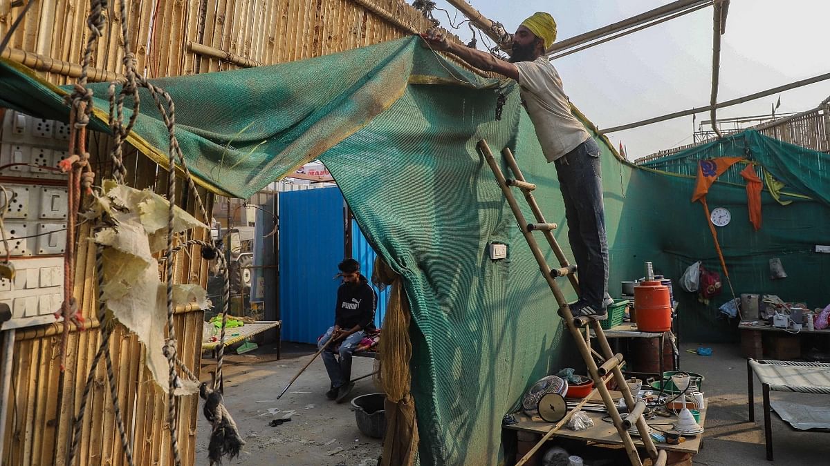 A farmer dismantles a temporary structure from a highway at the Delhi-Haryana state in Singhu formally ending year-long mass protests. Credit: AFP Photo