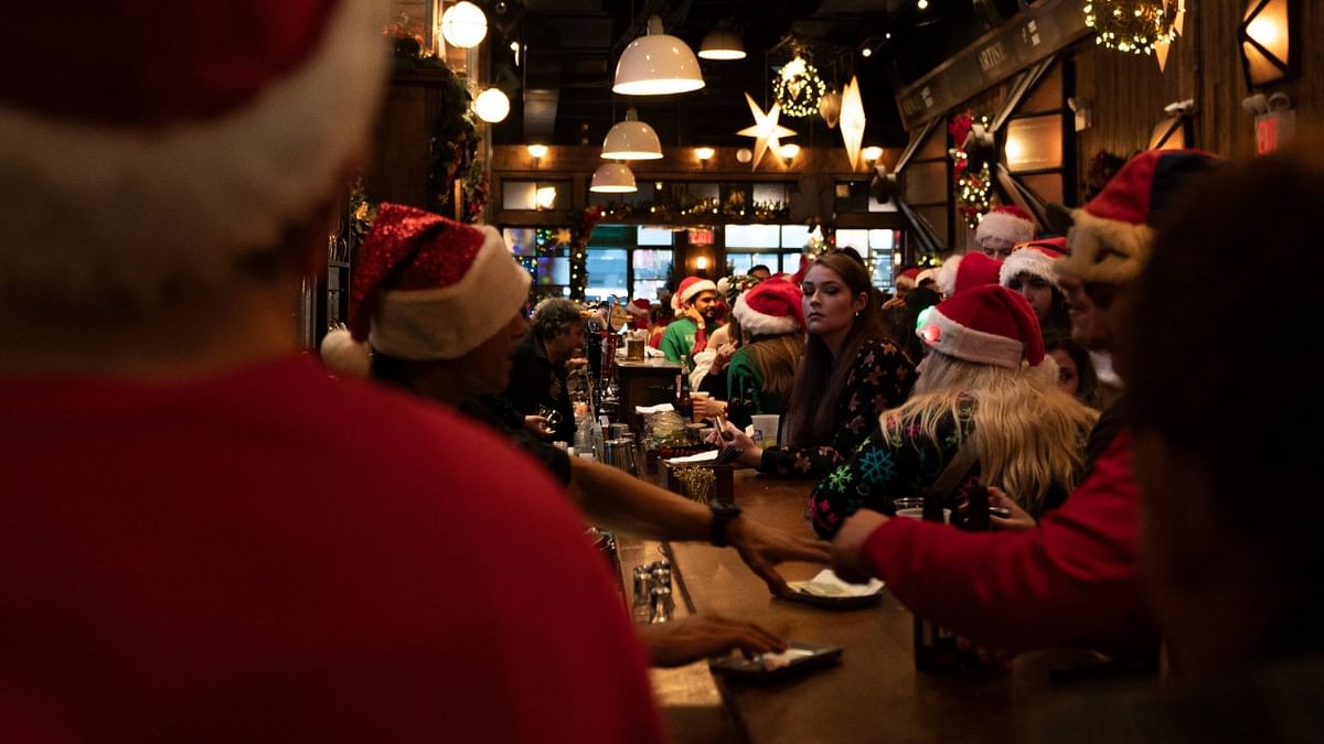 People dressed in Santa Claus costumes order drinks at Mustang Harry's during SantaCon in New York. Credit: AFP Photo