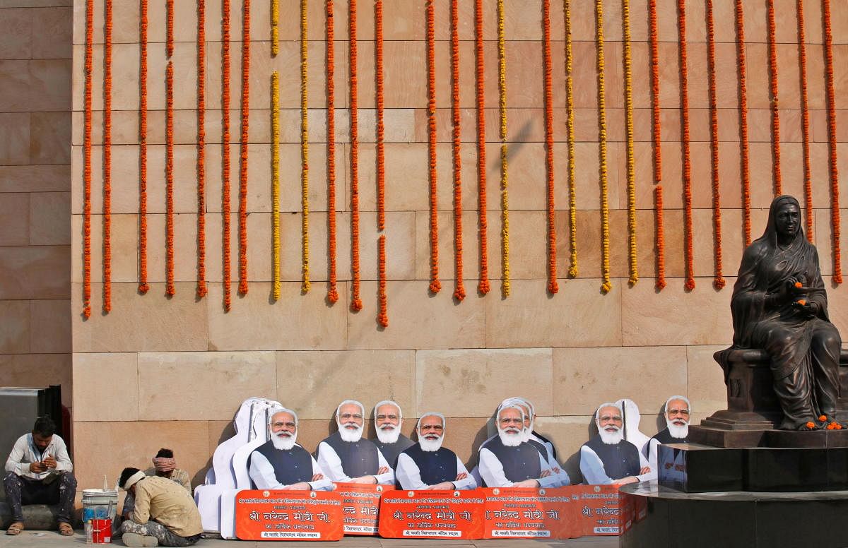 Workers sit next to cut-outs of Prime Minister Narendra Modi inside Kashi Vishwanath Temple premises. Credit: Reuters Photo