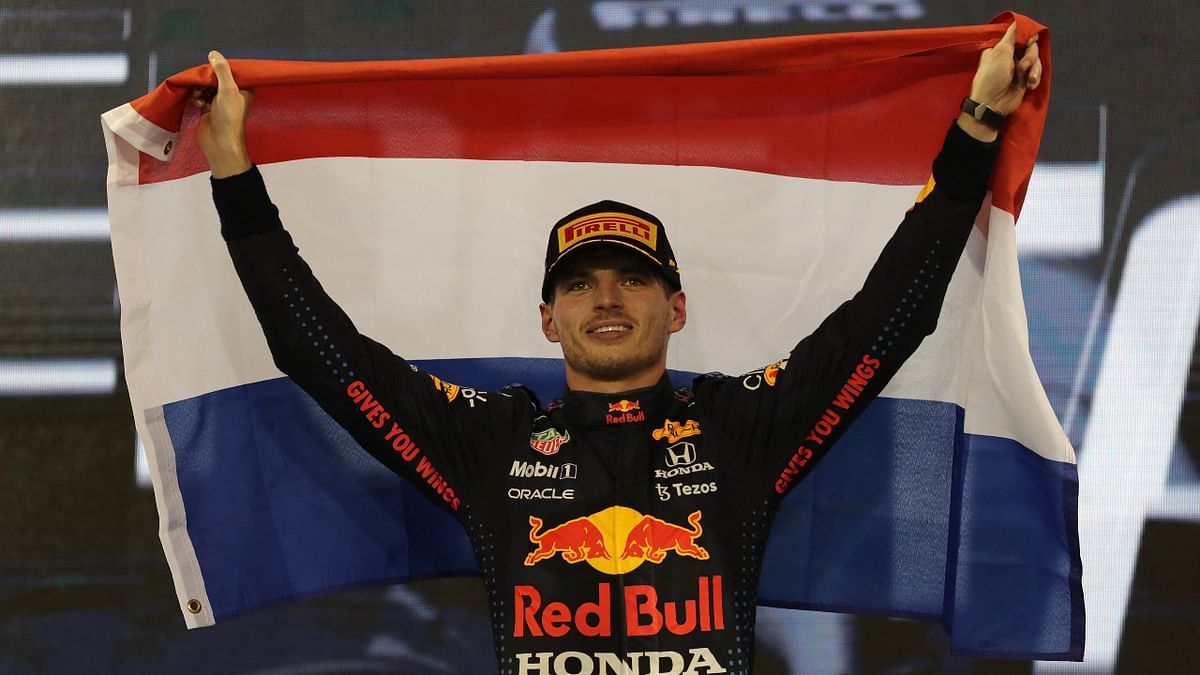 Red Bull's Max Verstappen celebrates winning the race and the world championship on the podium with a Netherlands flag. Credit: Reuters Photo