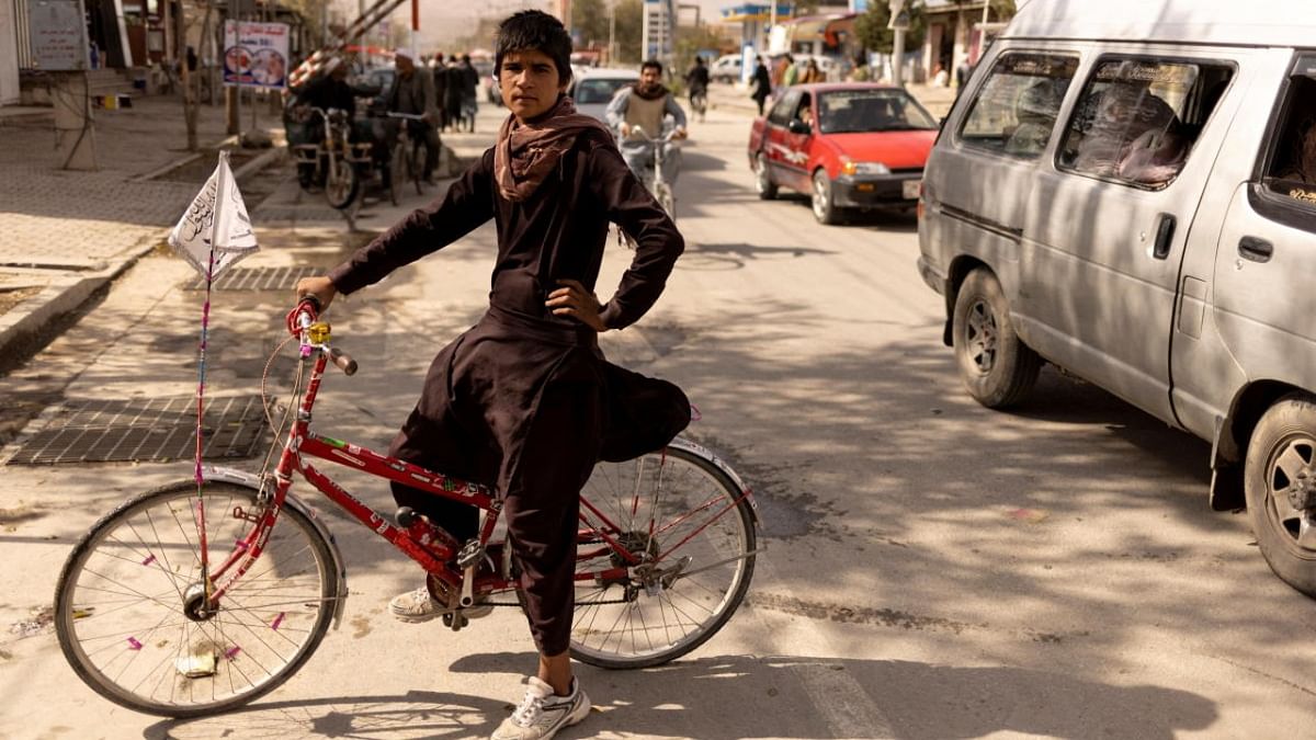 Wafiullah, 15, from Maidan Wardak province, sits on his bike that has an Islamic Emirate flag hanging on it, as he poses for a photo in front of a Taliban checkpoint in Kabul. Credit: Reuters photo