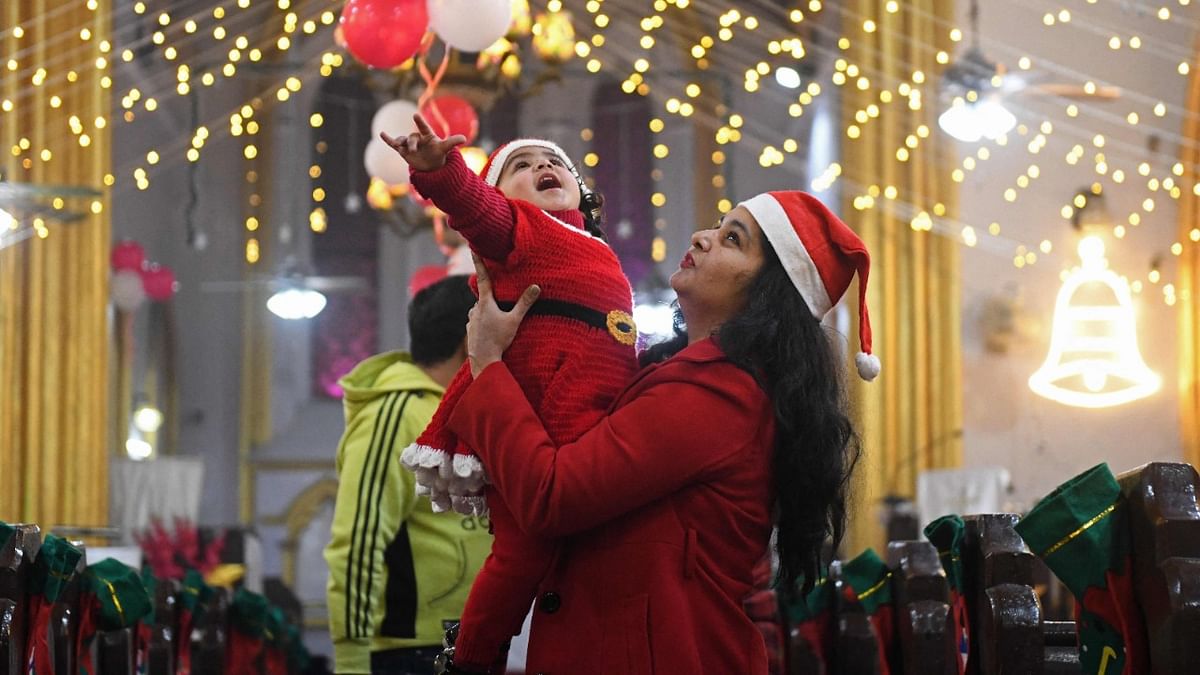 A child dressed as Santa Claus is held up by her mother on the eve of Christmas at St Paul's church in Amritsar. Credit: AFP Photo