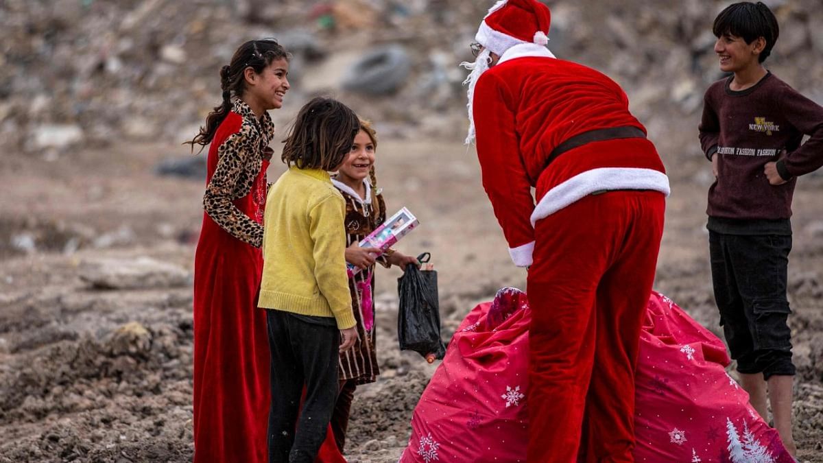 Mohamed Maarouf, 28, while dressed in a Santa Claus costume, distributes Christmas gifts to impoverished children living in slums near the centre of Iraq's southern city of Basra. Credit: AFP Photo