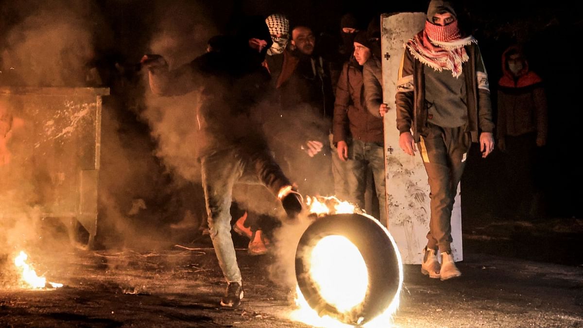 A Palestinian protester rolls a burning tire towards Israeli forces during clashes following a demonstration against the return of Jewish settlers to their area by the illegal Israeli outpost of Homesh near the Palestinian village of Burqah in the occupied West Bank. Credit: AFP Photo