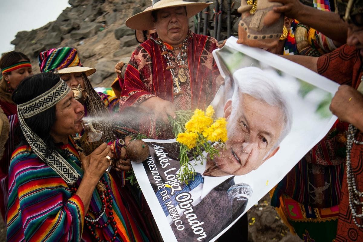 Shamans performing a ritual of predictions for the coming year display a poster of Mexican President Andres Manuel Lopez Obrador, at San Cristobal hill in Lima. Credit: AFP Photo