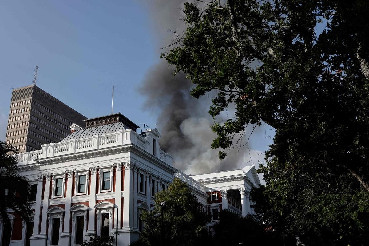 Smoke billows from the roof of a building at the South African Parliament precinct in Cape Town during a fire incident. Credit: AFP Photo