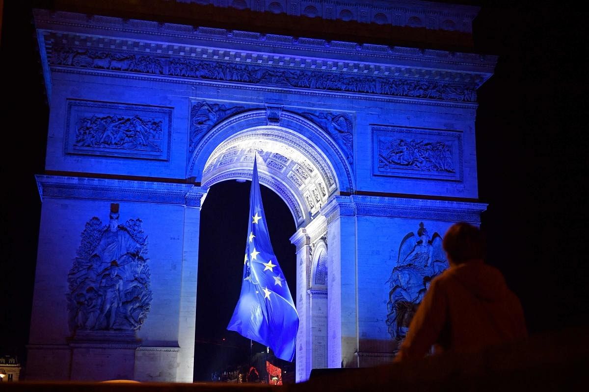 People gather at the Arc de Triomphe lit up in blue to mark the French presidency of the European in Paris. Credit: AFP Photo