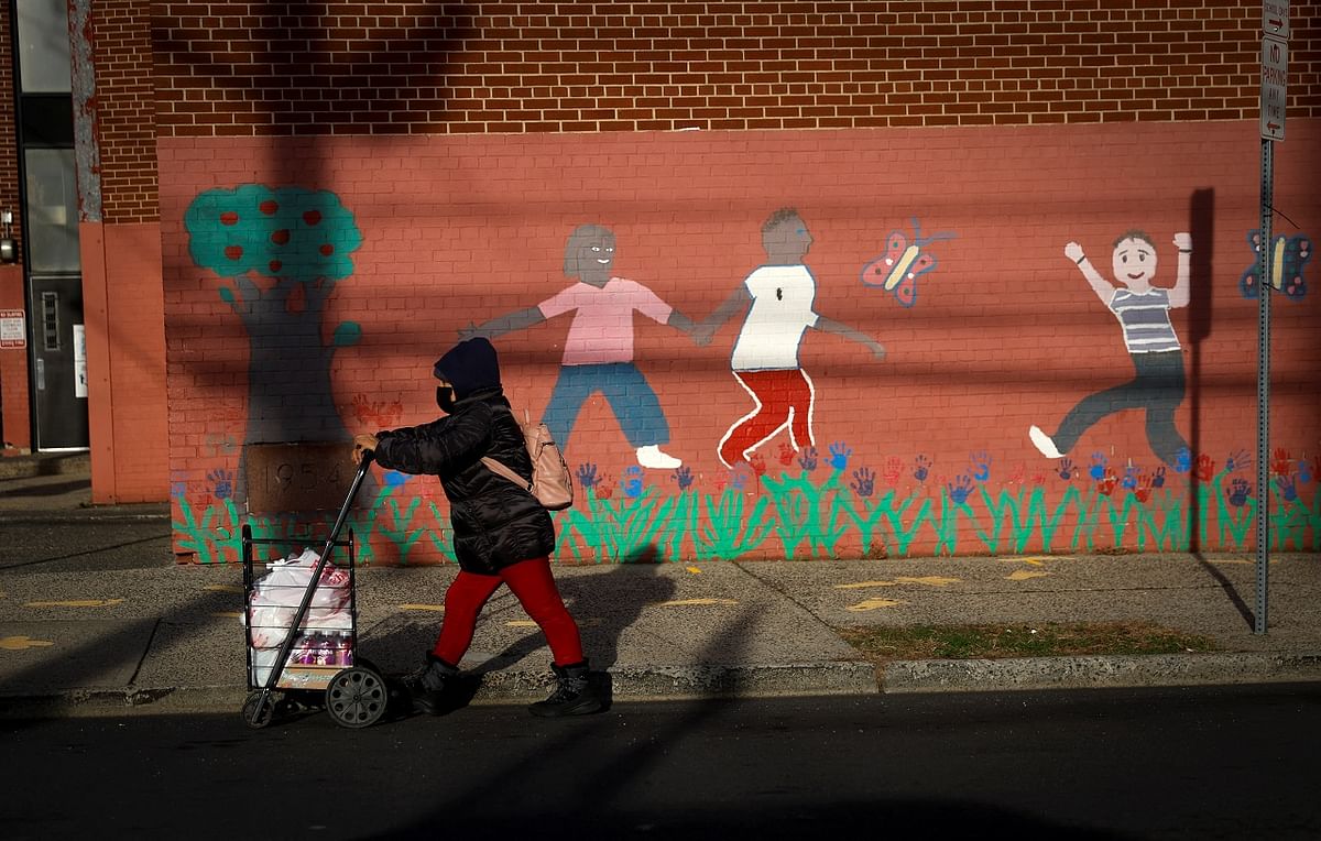 A woman wearing a protective face mask walks past an empty closed school after the city of Newark ordered students to return to remote instruction due to the spread of coronavirus disease. Credit: Reuters Photo