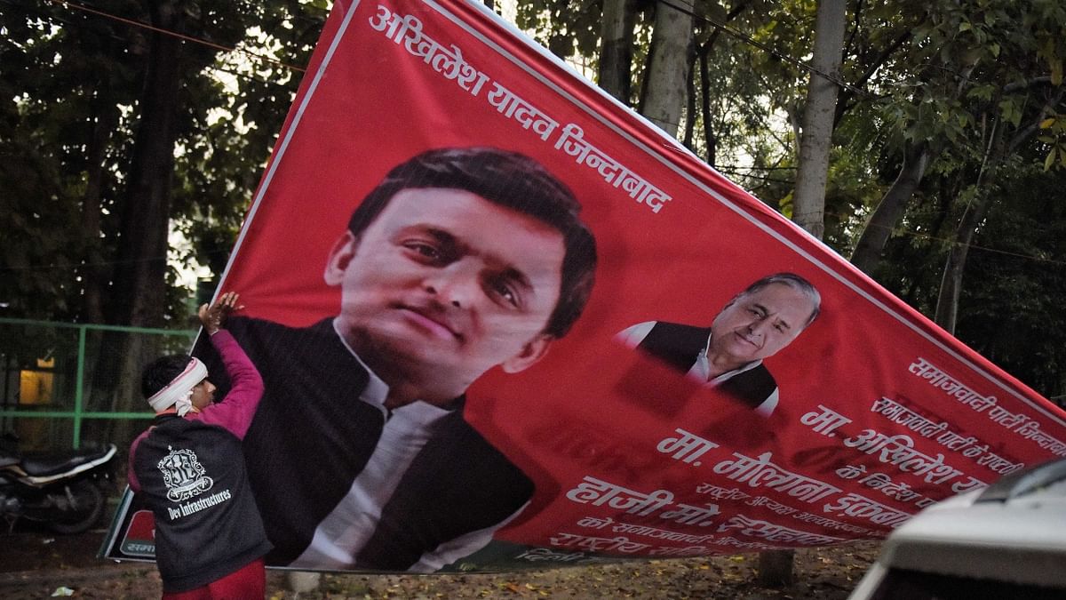 A UP administration worker removes a banner of Akhilesh Yadav, in Lucknow. Credit: PTI Photo