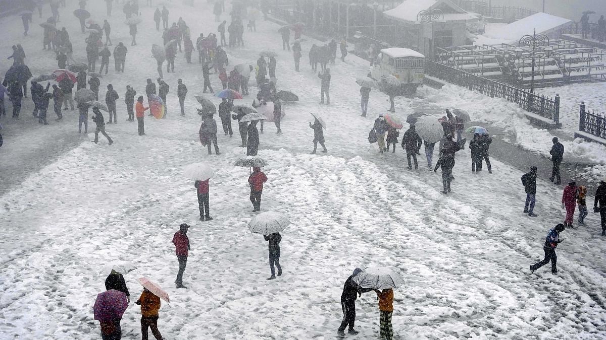 Tourists are seen enjoying a walk at The Ridge during snowfall in Shimla. Credit: PTI Photo