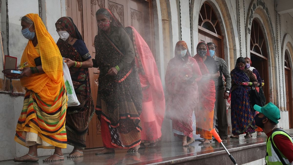 A man wearing a protective mask sprays disinfectant on pilgrims as they arrive to take the holy dip at the Sagar Island, amidst the spread of the coronavirus disease (Covid-19) in the eastern state of West Bengal. Credit: Reuters Photo